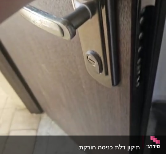 ידית דלת מתכתית על דלת עץ פתוחה